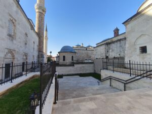 Solda Üç Şerefeli Camii, arkada Saatli Medrese. sağda Peykler Medresesi ve ortadaki kubbeli yapı Hacı İzzet Paşa Türbesi 